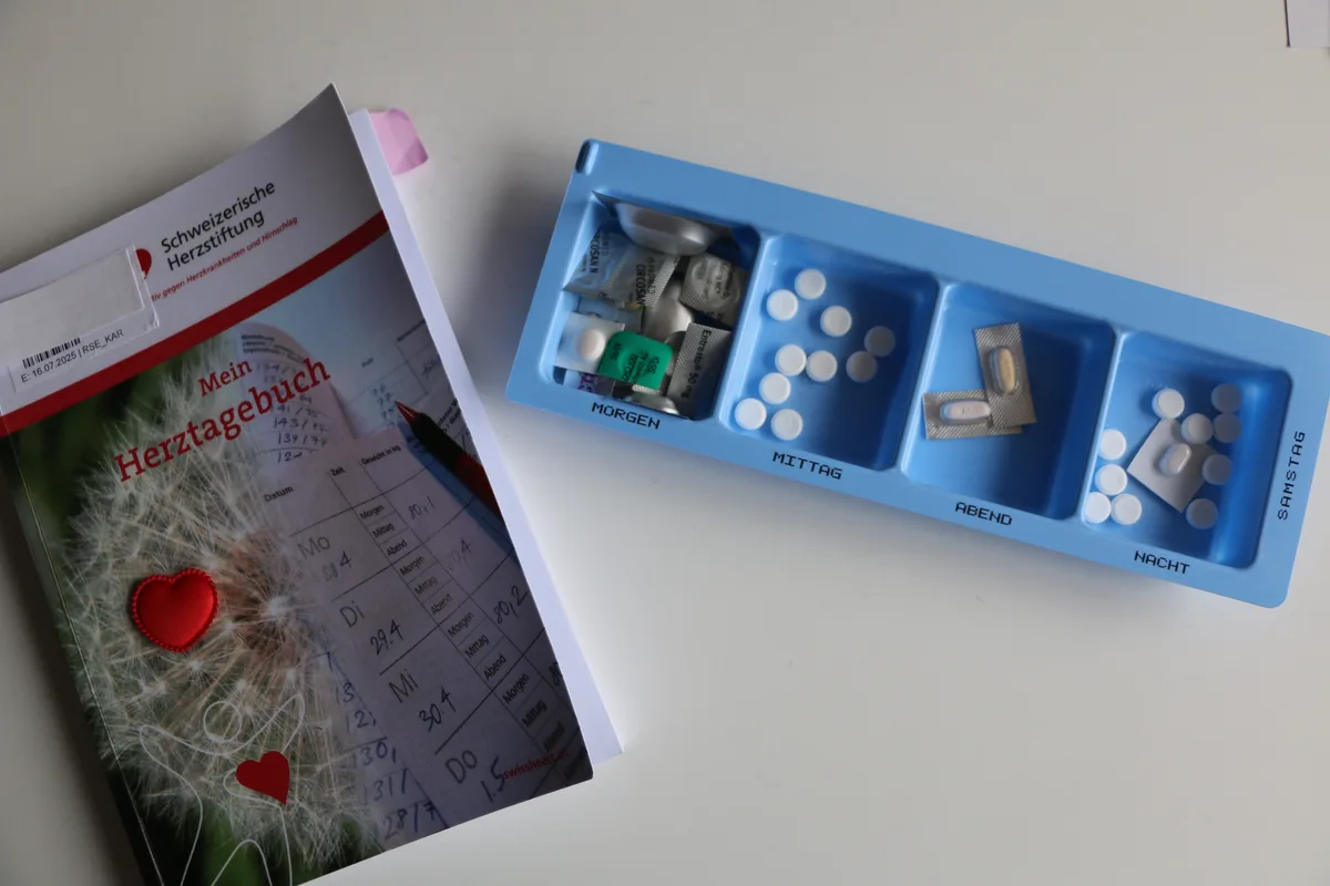 Herztagebuch und ein Dispenser mit vielen Tabletten.